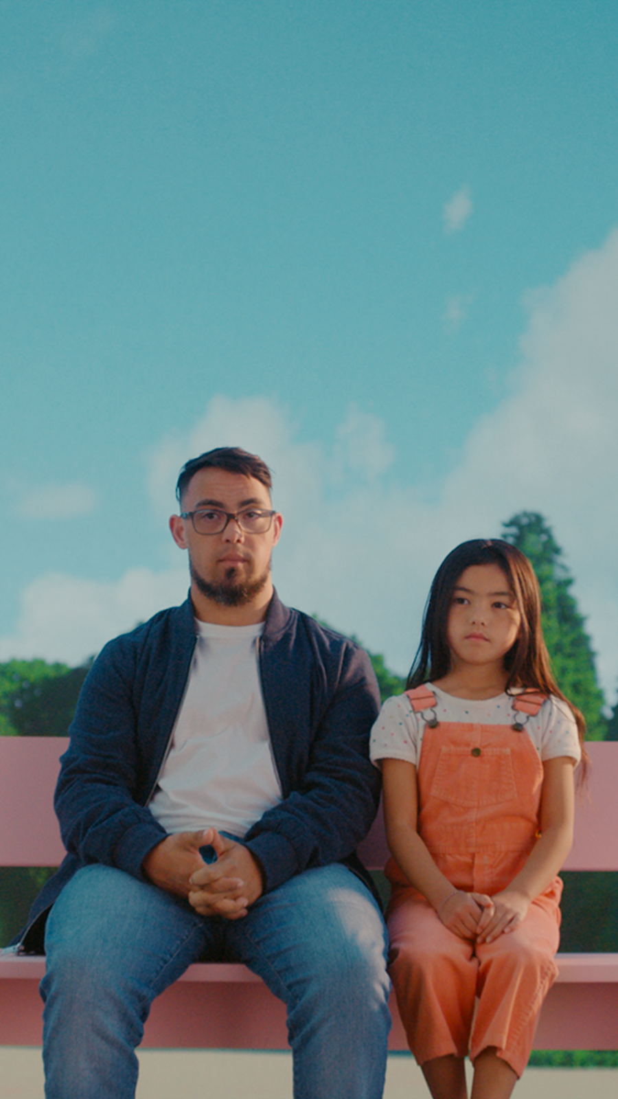 Man and girl sit on park bench