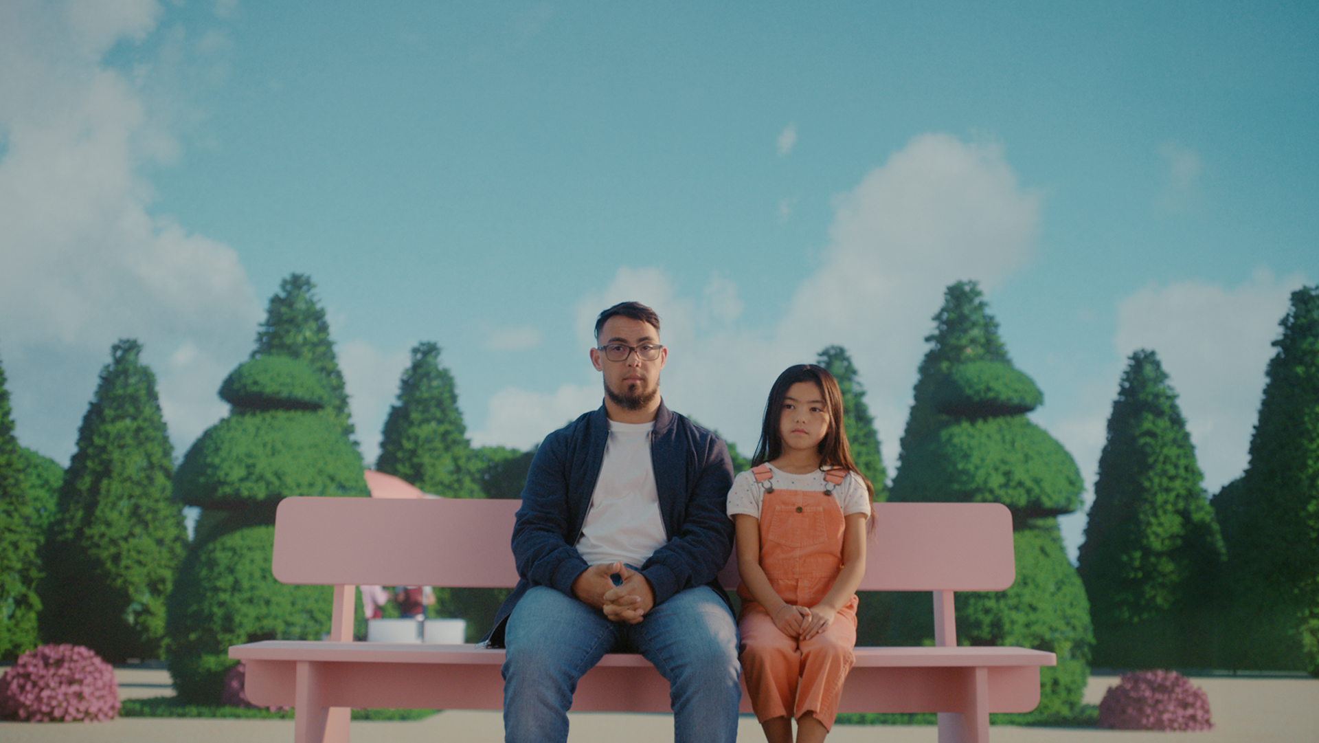 Man and girl sit on park bench