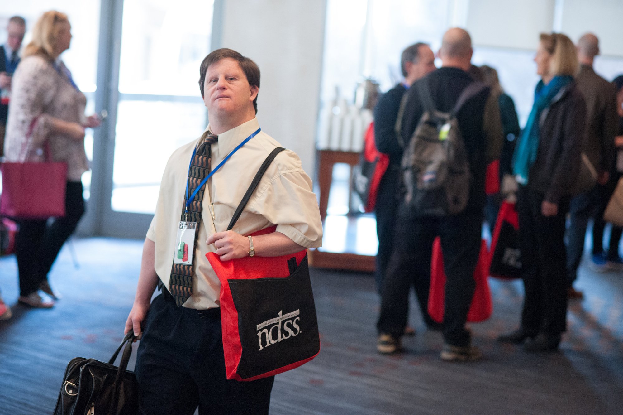 adult summit conference photo of man holding bag at conference