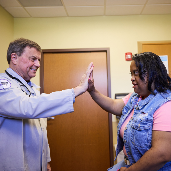 A woman with Down syndrome high-fives her doctor