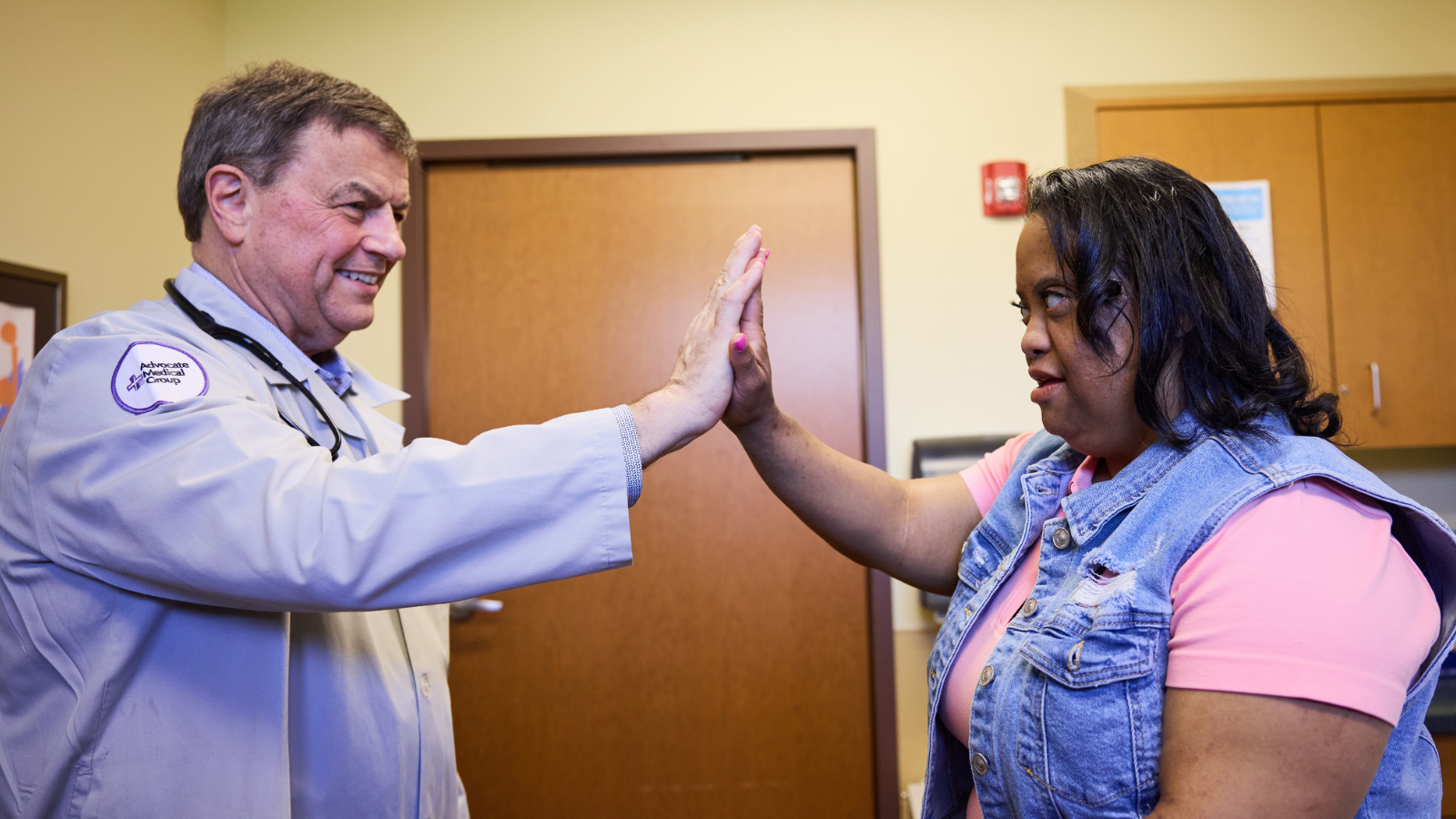 A woman with Down syndrome high-fives her doctor.