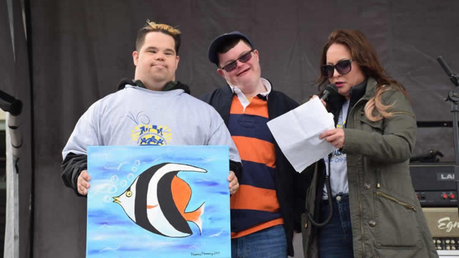 Young man holds up fish artwork.