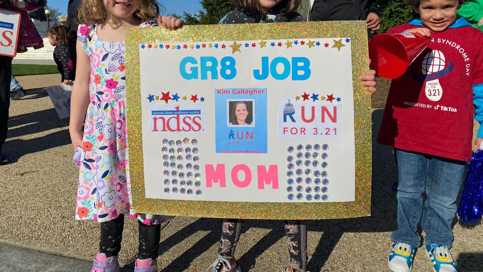 kids with a sign cheering on mom