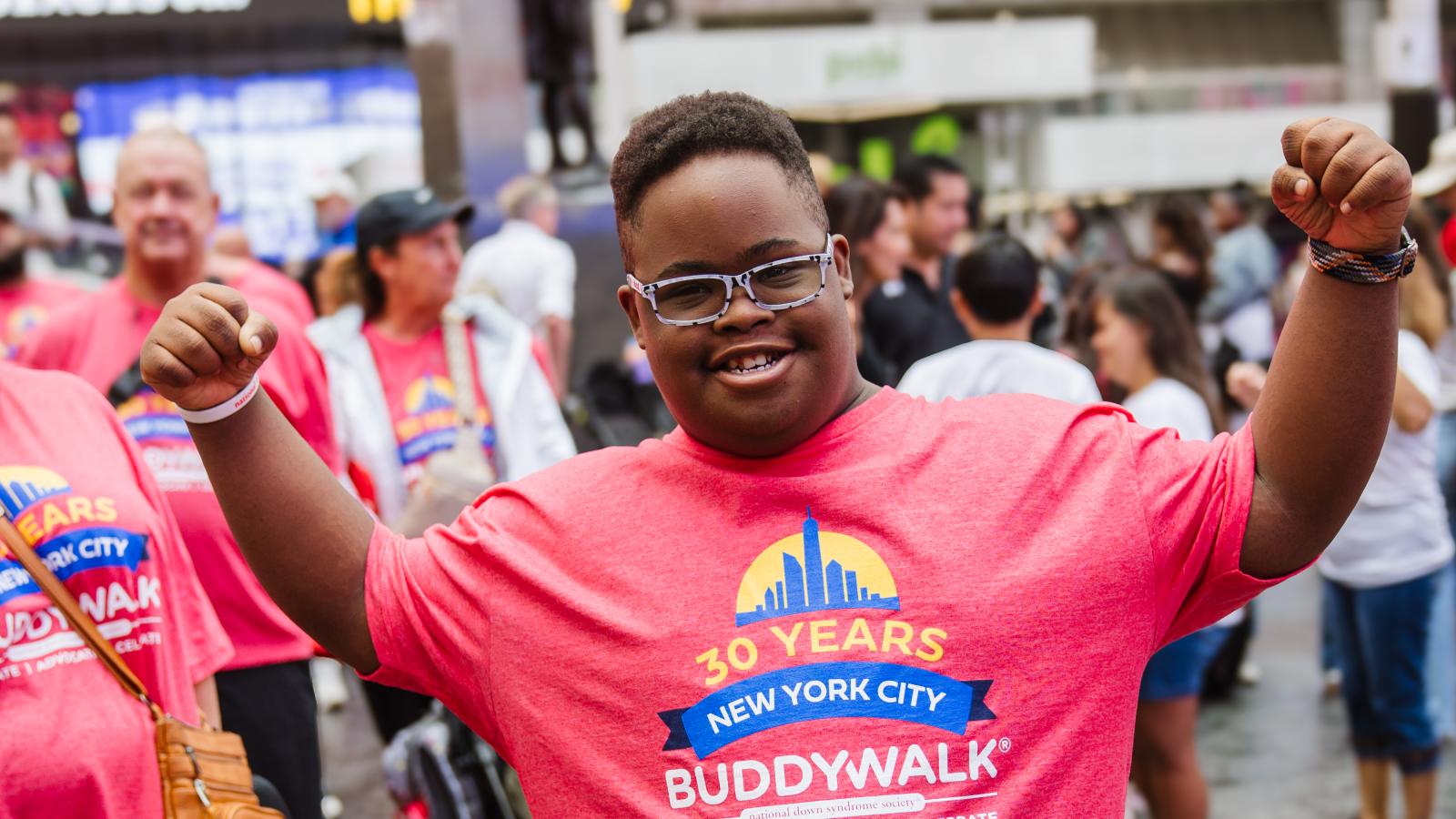 black man with down syndrome smiles at the camera in his pink buddy walk shirt