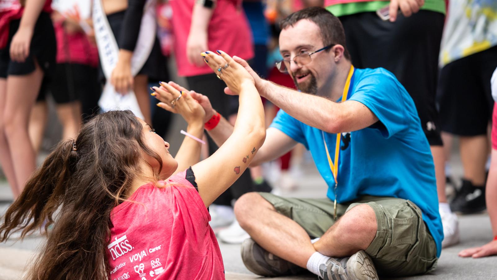 man with Down syndrome high fives women without Down syndrome