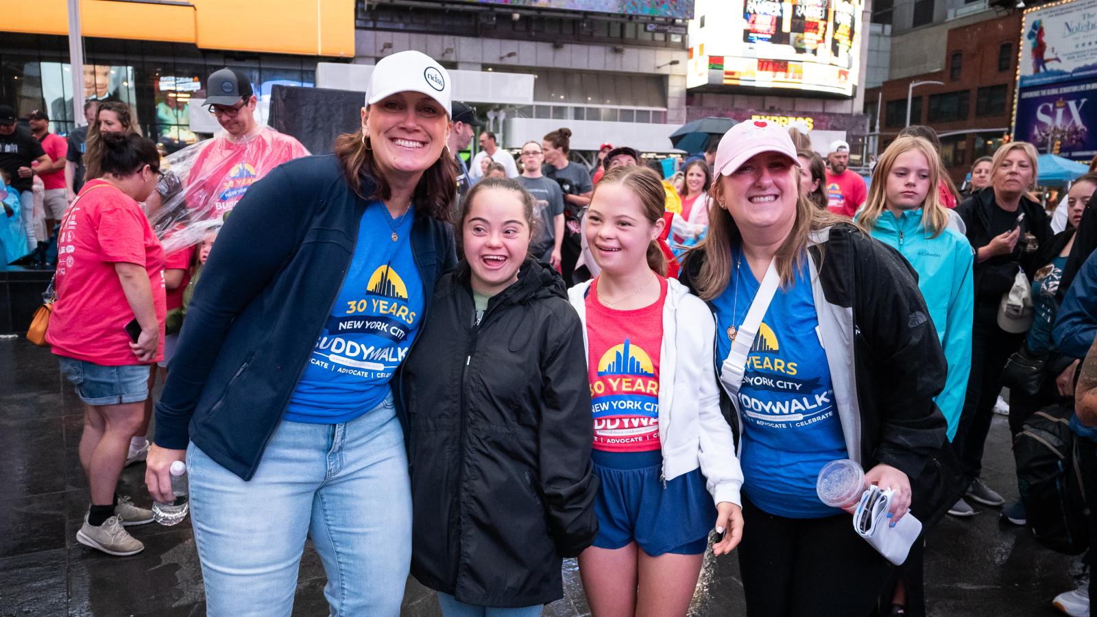 NDSS staff and a woman and a teen girl with Down syndrome smile at the camera from Times Square