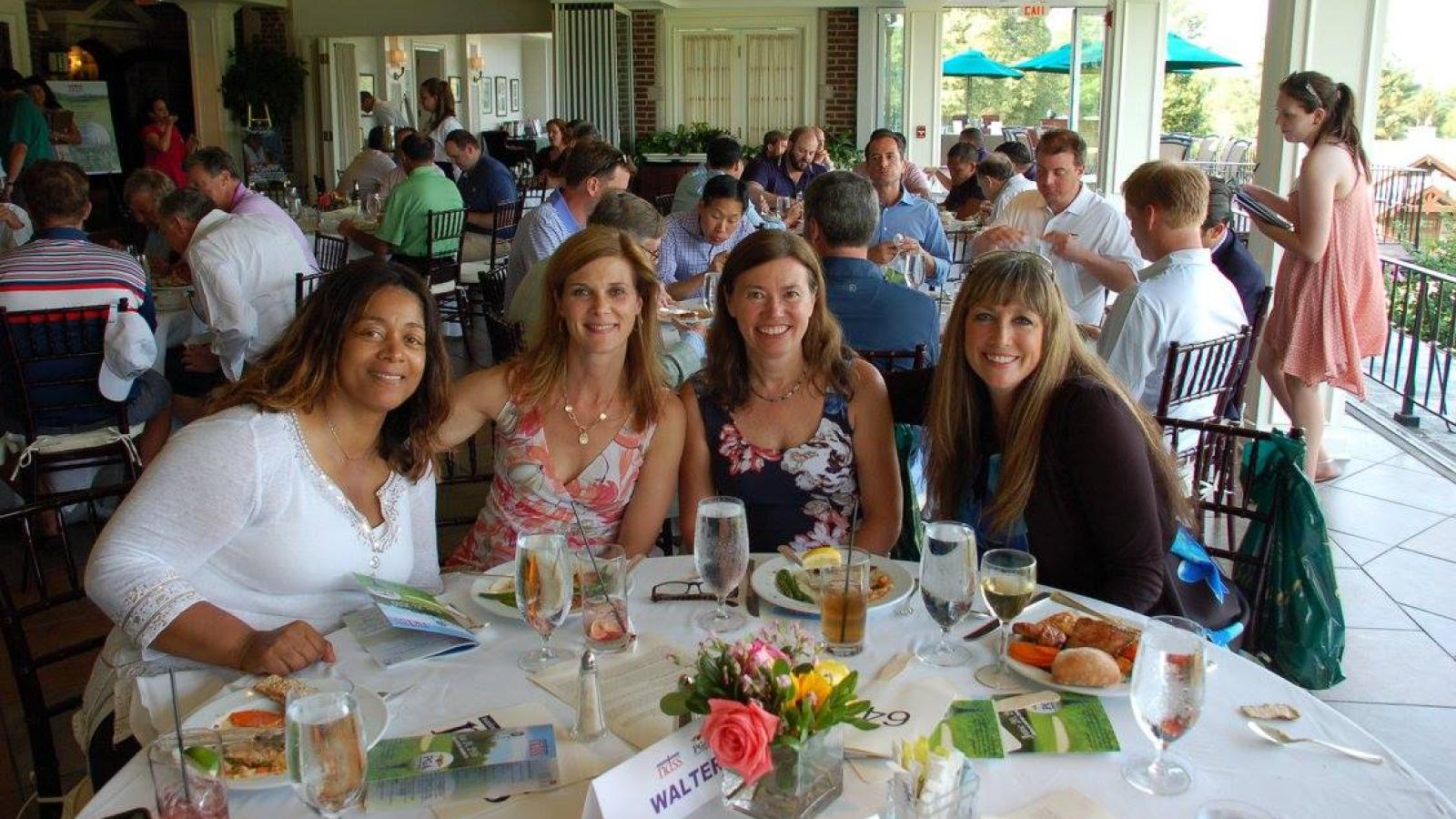 Four women smile at a banquet table