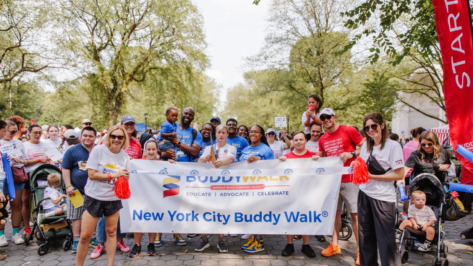 A group gathers at the start line of the Buddy Walk with a large banner