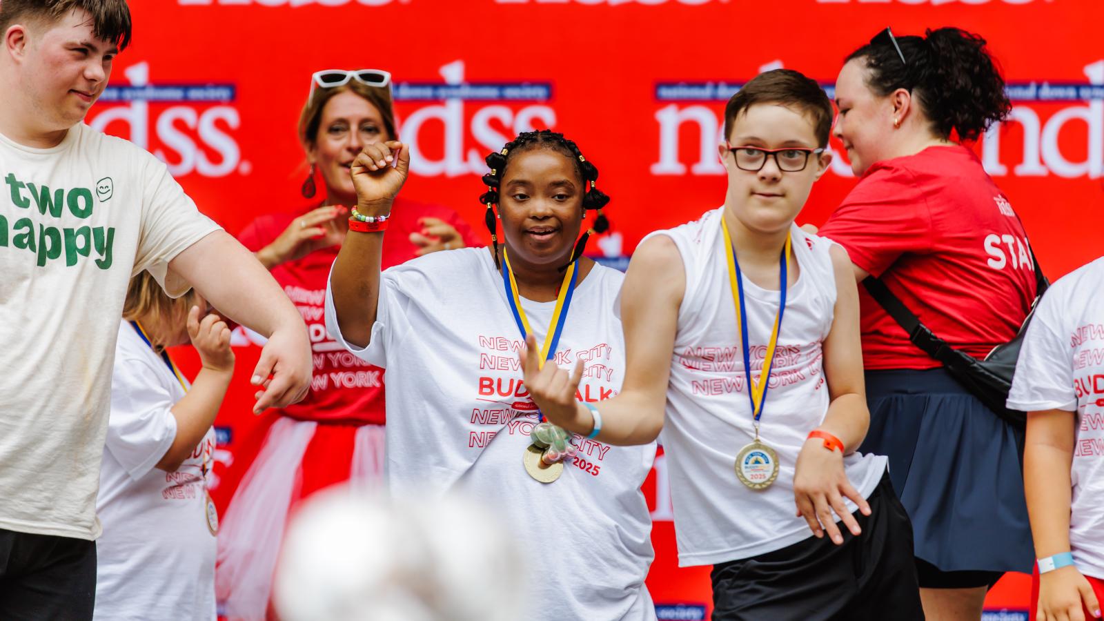 A group of individuals with Down syndrome dance on a stage in Central Park