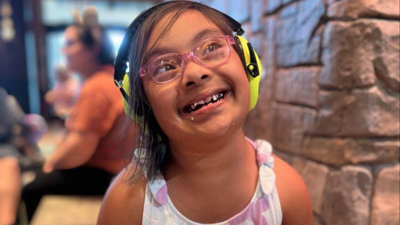 Young girl wearing headphones smiling at Family Weekend 2025