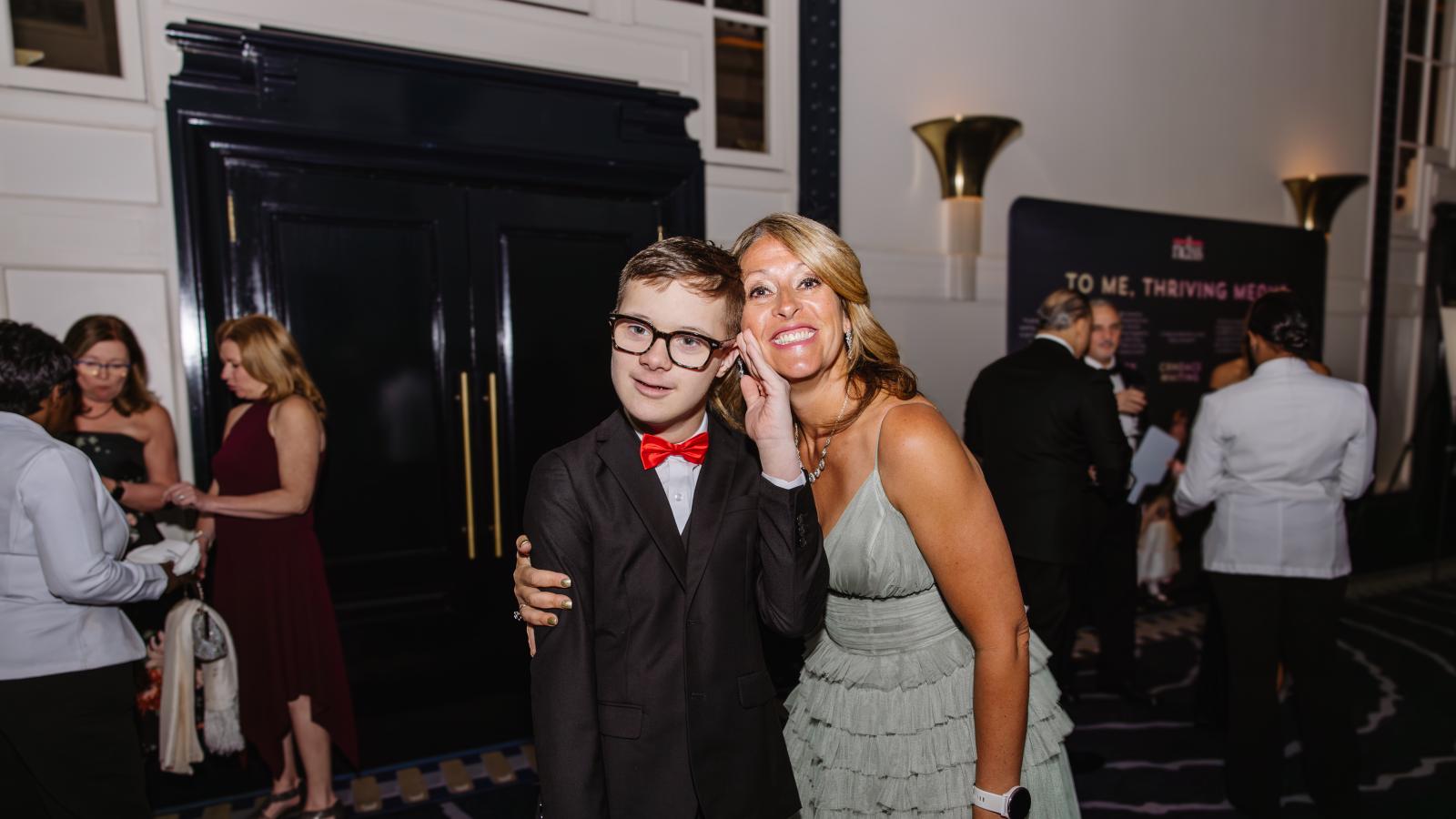 A boy with Down syndrome and a woman smile at the gala