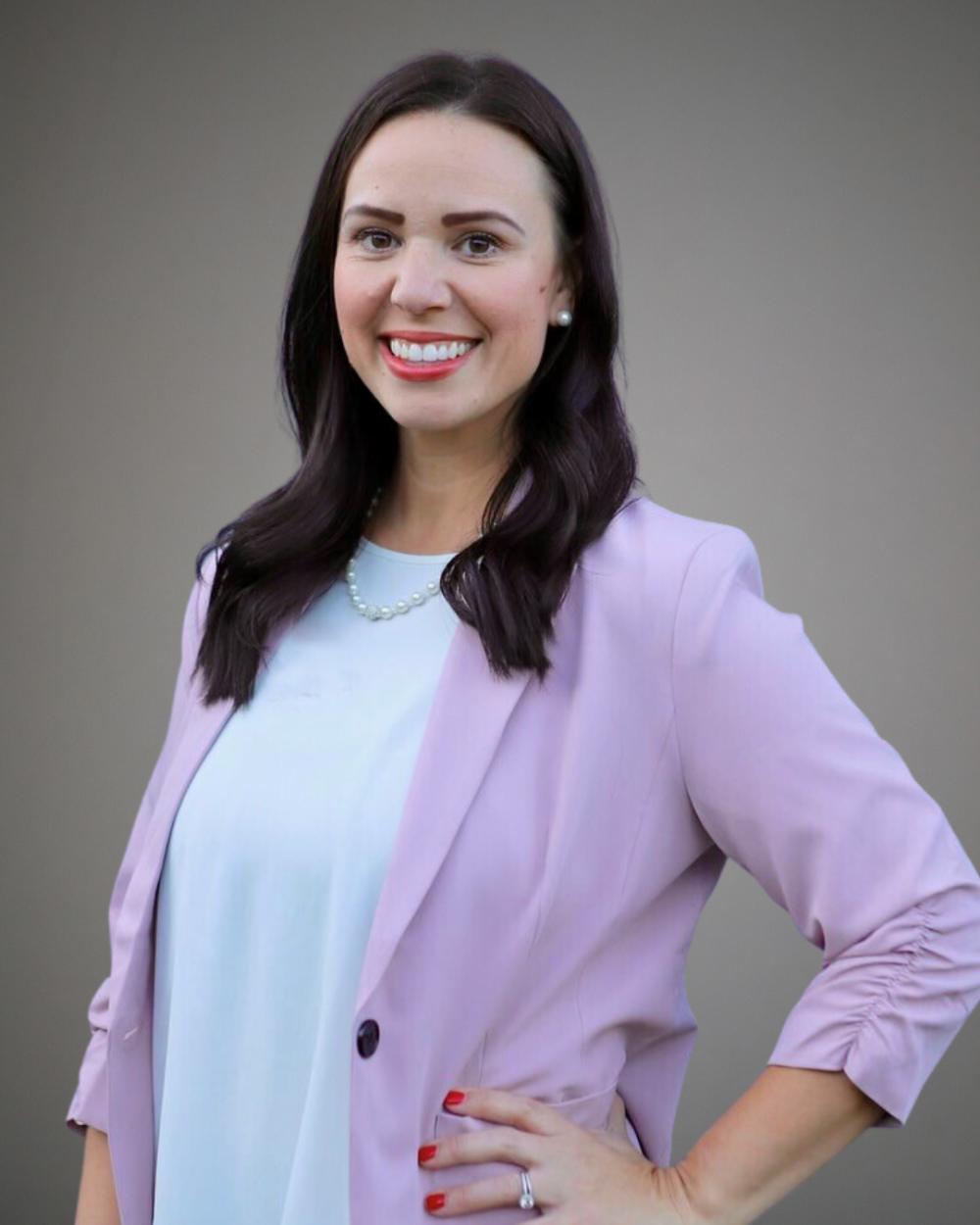 Amy Drow smiling in headshot with pink blazer, white top, and hand on hip