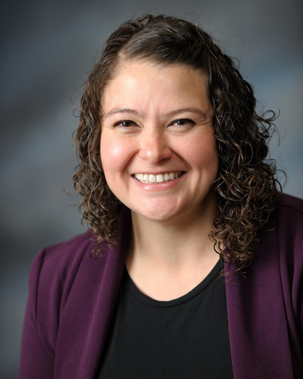 Headshot of Dr. Laura Mattie, a woman with brown hair, wearing a black bouse with a plum blazer.
