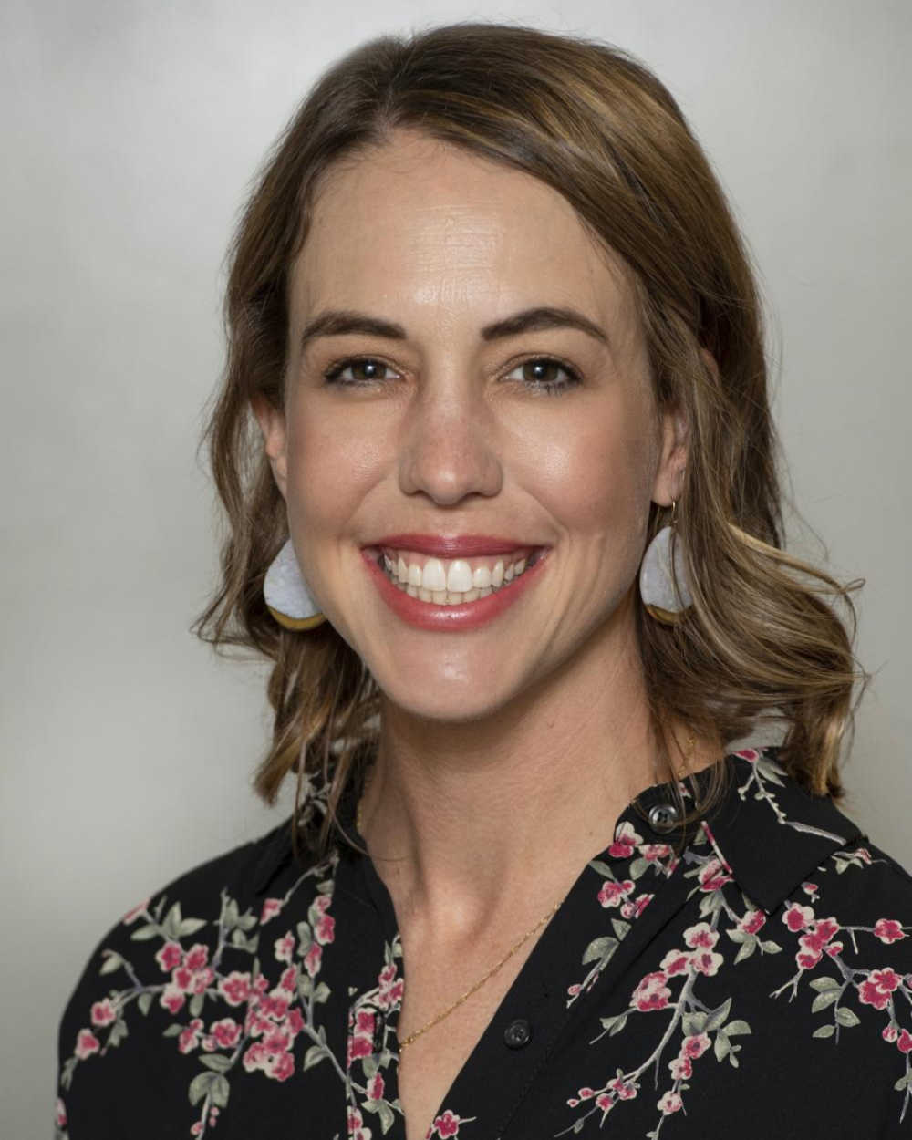 Headshot of Dr. Lauren Wang, a woman with light brown hair and a black blouse with pink flowers on it.
