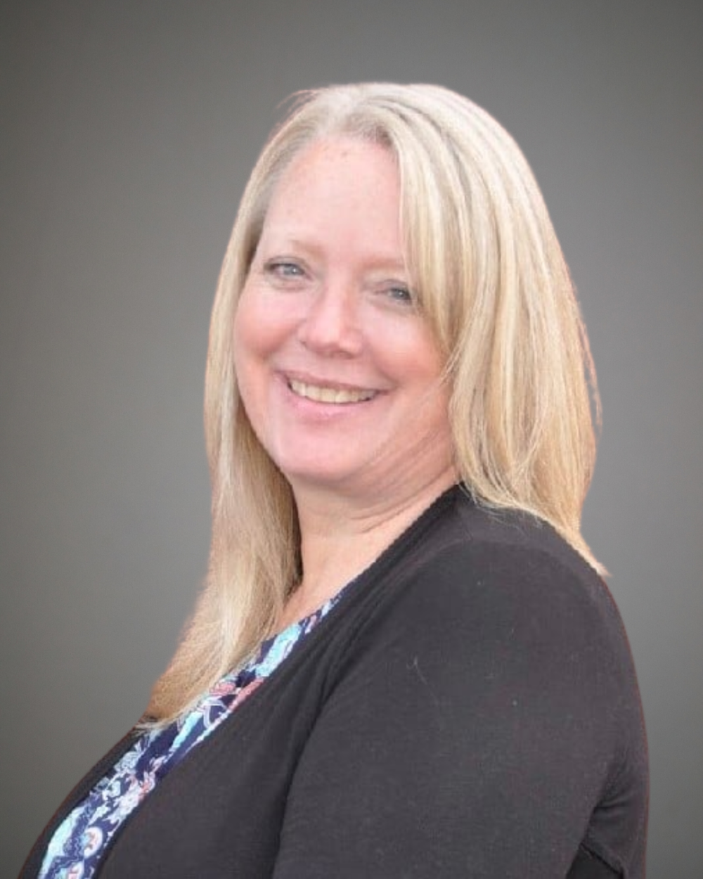 Headshot of Janice Fountaine, a woman with light blonde hair, wearing a multicolored blouse and a black blazer.