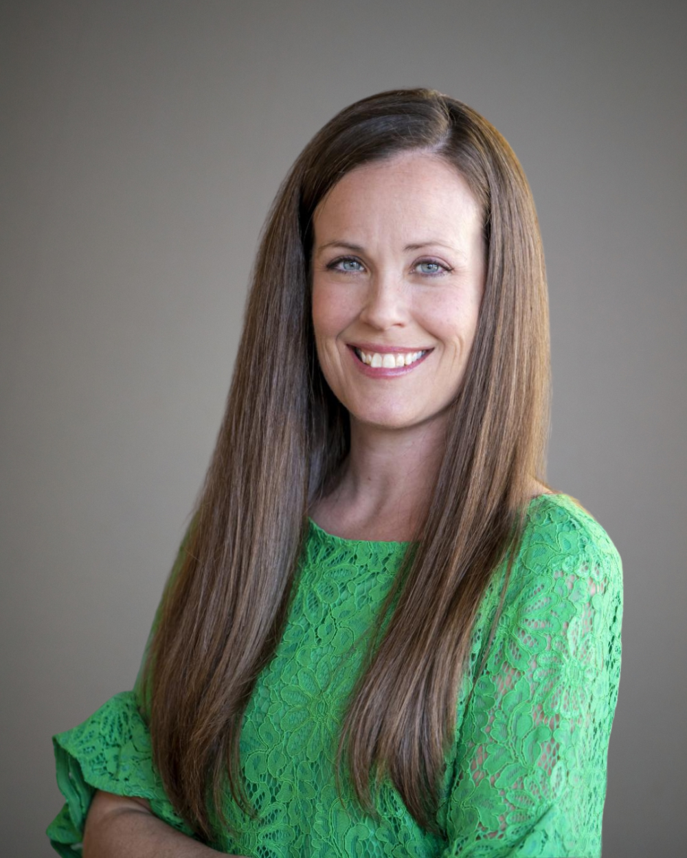 Headshot of Jessica Kuss, a woman with straight brown hair, wearing a bright green blouse.