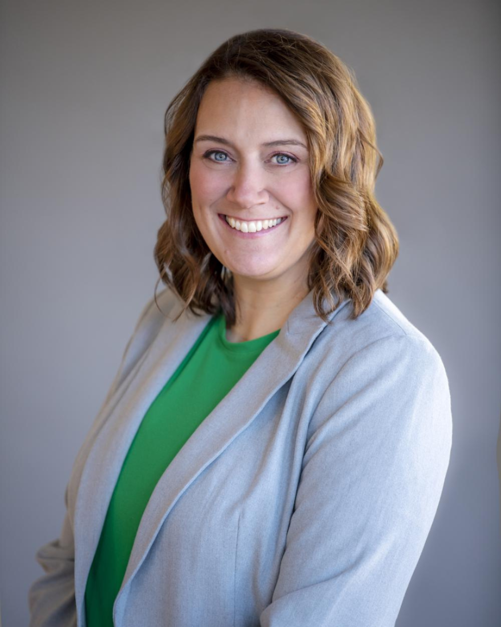Headshot of Kandi Pickard, a woman wearing a green blouse and grey blazer.