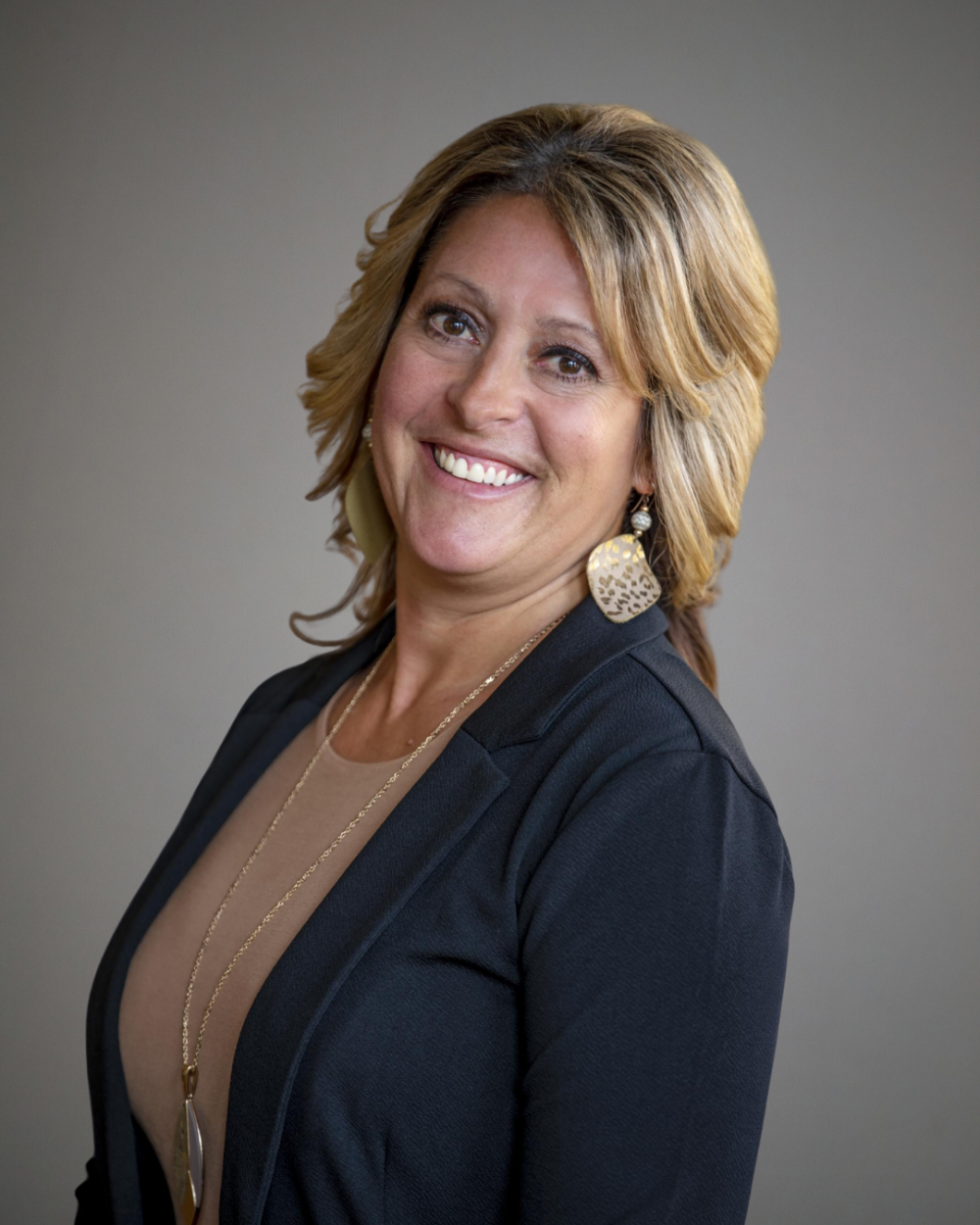 Headshot of Misty Adams, a woman with blonde hair wearing a beige blouse, black blazer, and gold drop earrings.