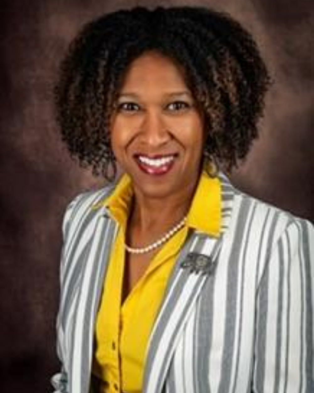 Headshot of Schunda Jones-Murphy, a woman with brown hair, wearing a peach button up shirt, a striped blazer, and a pearl necklace.