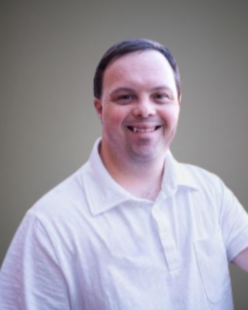 Headshot of David DeSanctis, a man with Down syndrome, wearing a white collared shirt.