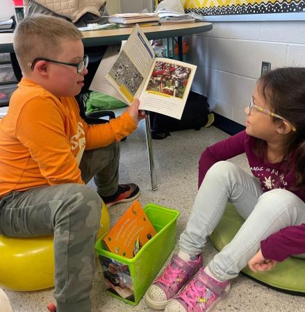 photo of child with down syndrome reading to his friend with down syndrome