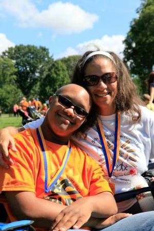 A man with Down syndrome and a woman smile, wearing Buddy Walk ribbons