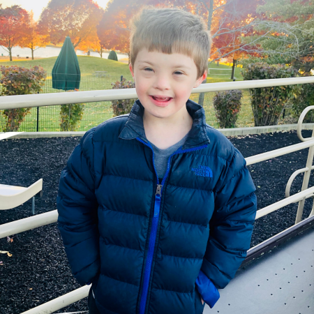 A photo of Collin Lis, an 11-year-old boy with Down syndrome standing outside on a fall day