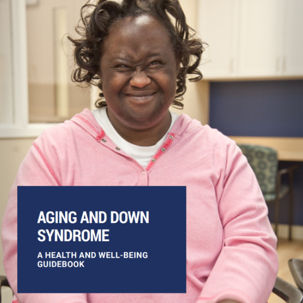 Image of a smiling Black woman with Down syndrome, wearing a light pink sweatshirt. Aging and Down Syndrome: A Health and Well-Being Guidebook