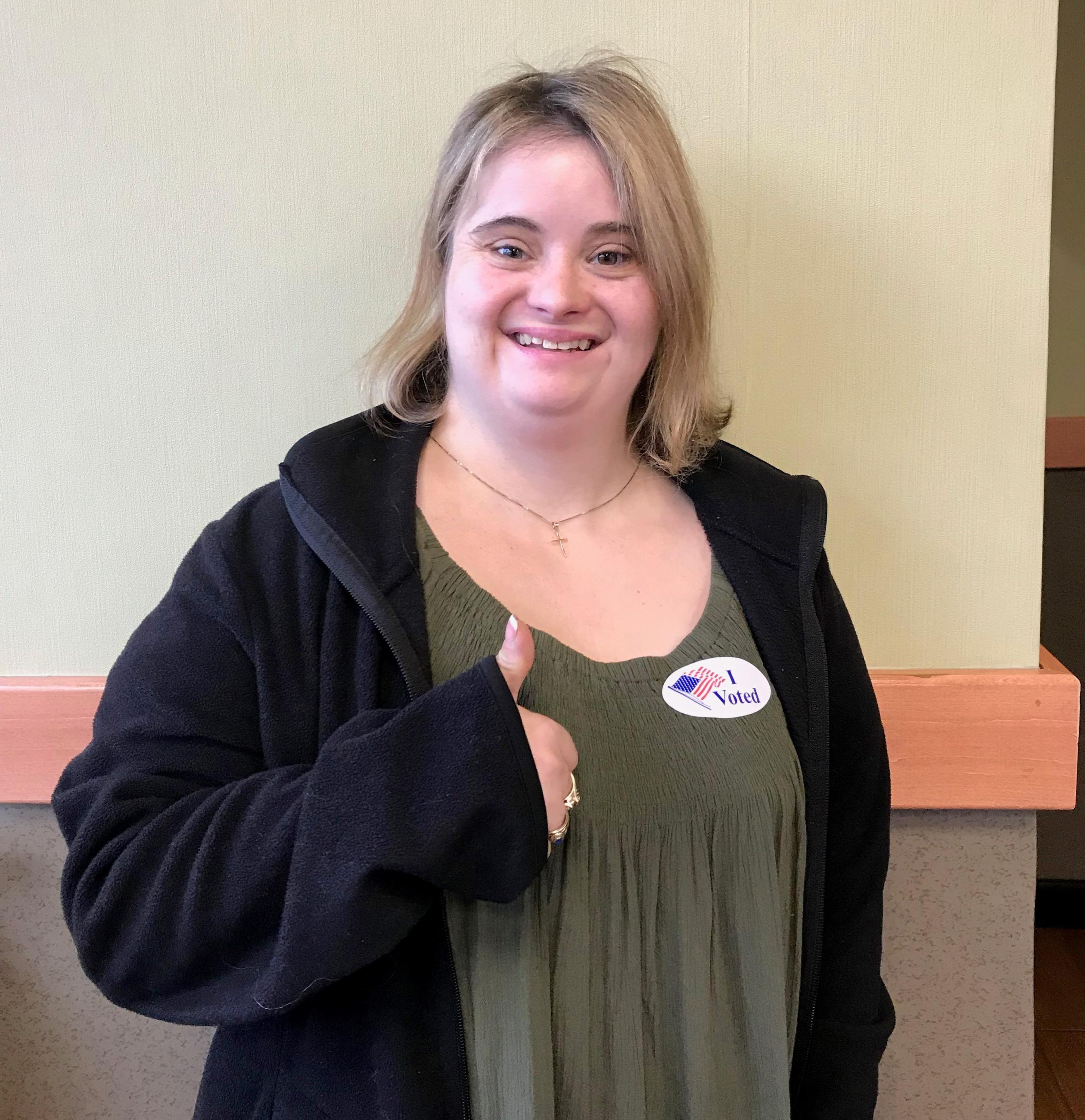 woman with down syndrome voting and giving thumbs up to camera