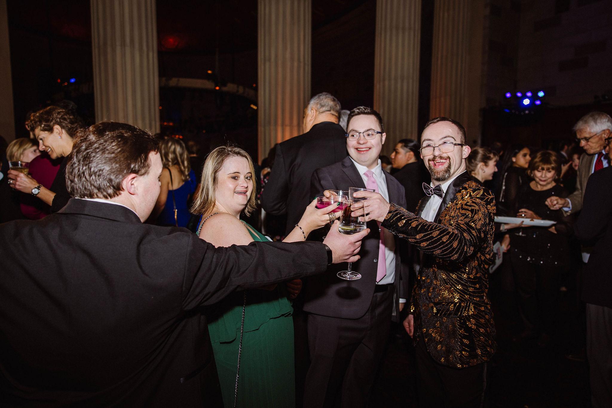 Image of friends with Down syndrome celebrating the gala with a "cheers"