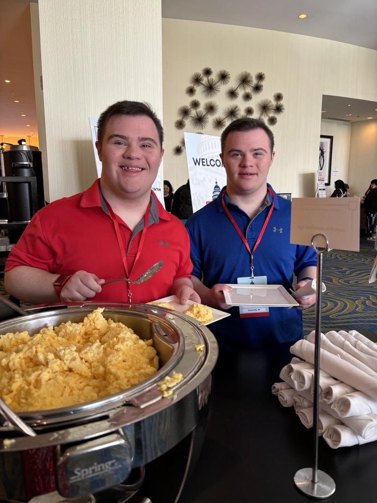 Two guys with Down syndrome get breakfast at a buffet at the NDSS Down Syndrome Advocacy Conference