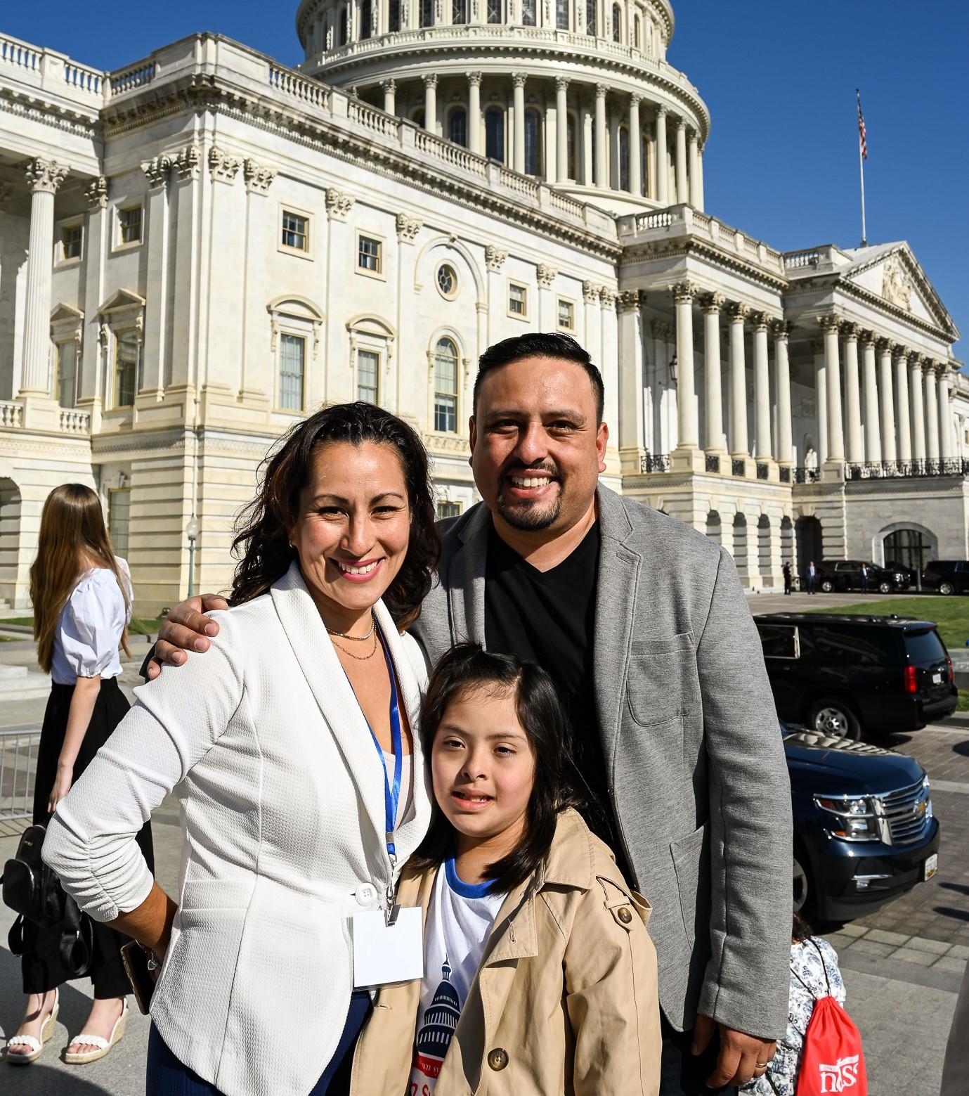 A girl with Down syndrome and her parents stand in front of the US Capitol Building