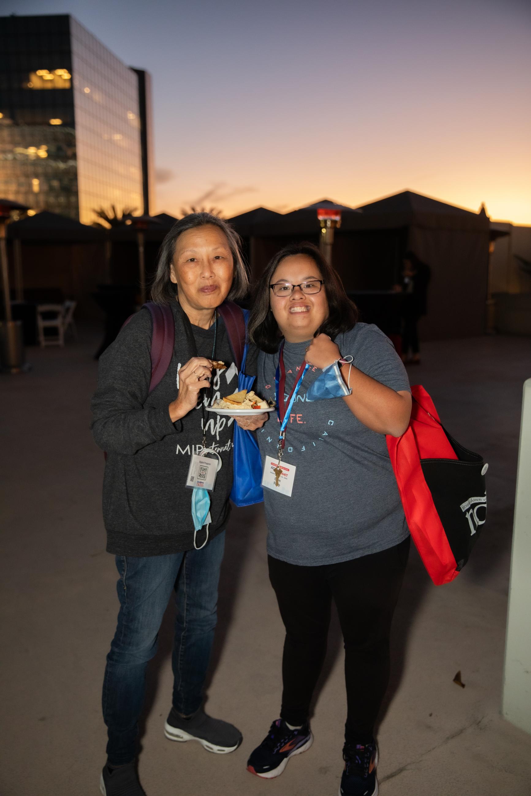 A mom and daughter with Down syndrome enjoy a snack at sunset at an NDSS Adult Summit social hour