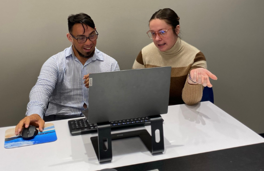 A man with Down syndrome and a woman without Down syndrome work on a computer together