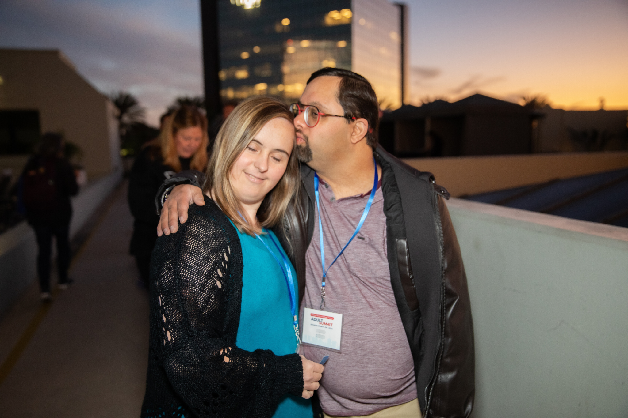 A man with Down syndrome kisses his girlfriend with Down syndrome on the forehead
