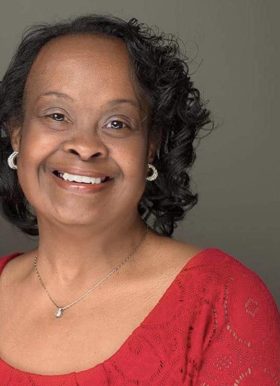 Woman with Down syndrome smiles and wears a red blouse