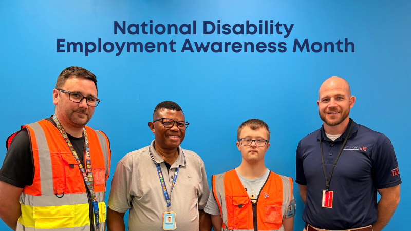 National Disability Employment Awareness Month. Photo of two men with Down syndrome and two men without Down syndrome. They all wear lanyards. Two wear bright safety vests.