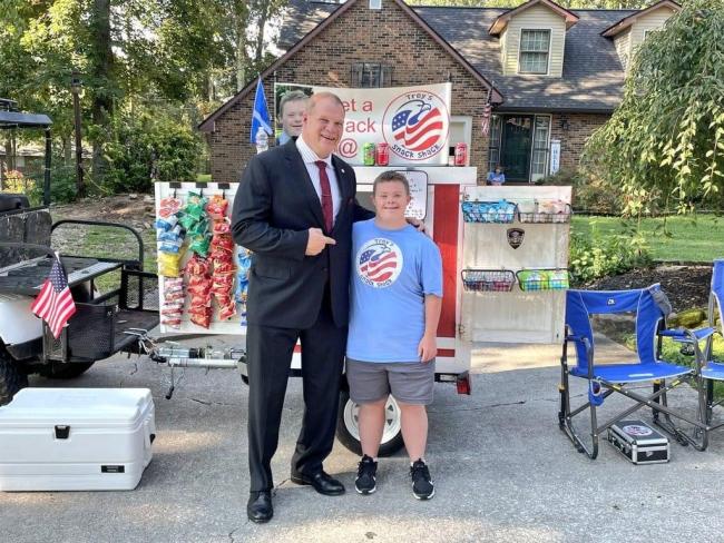 Trey Evans smiling standing with his business, a food stand