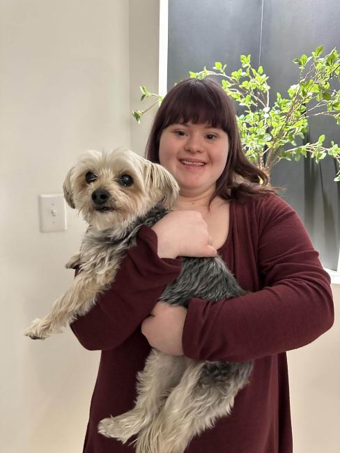 woman with Down syndrome smiling and holding a yorkie dog