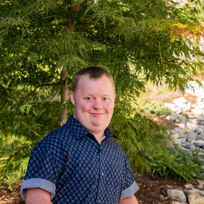 Man with down syndrome wearing a blue button down smiling at the camera