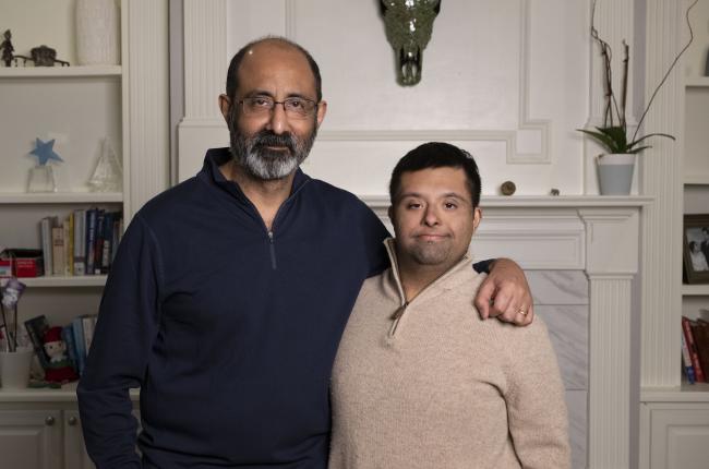 man with down syndrome and his father, posing in front of their fireplace