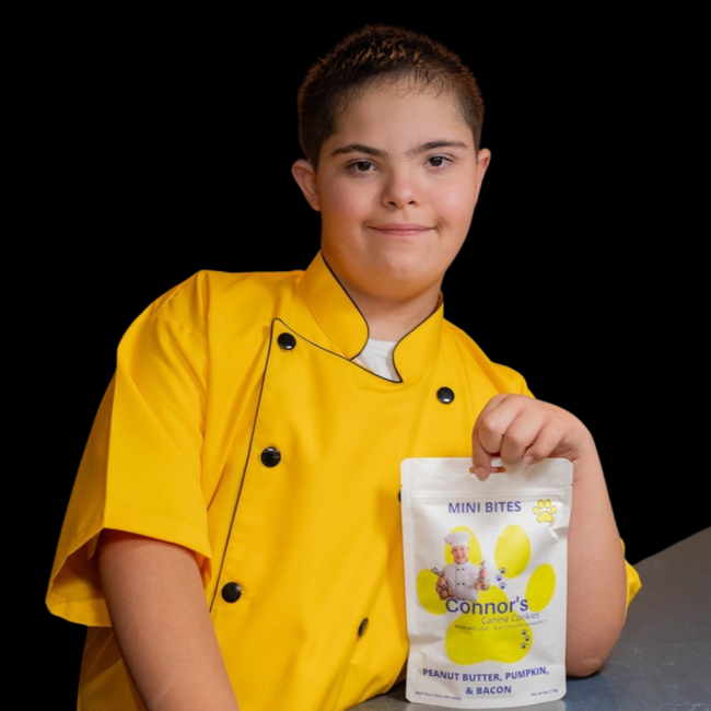 photo of a youg man with down syndrome wearing a chef outfit, holding his product, doggy treats