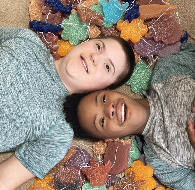 brothers with down syndrome lay down and smile at the camera