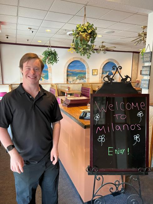 Image of Robert Padgett Jr, a man with Down syndrome, standing proudly at a restaurant.