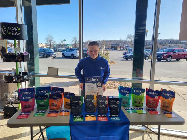 A young man with Down syndrome stands at a pet treats table