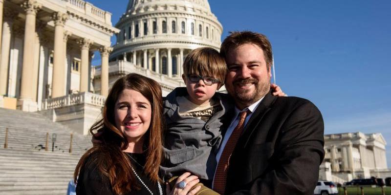 Parents hold their boy with Down syndrome in front of the capitol building